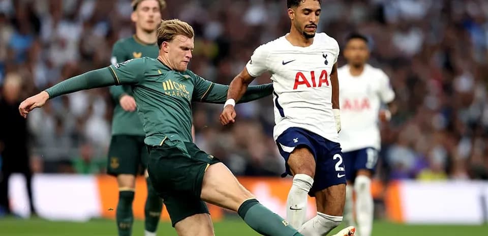 Jugador de Tottenham driblando mientras es tackleado