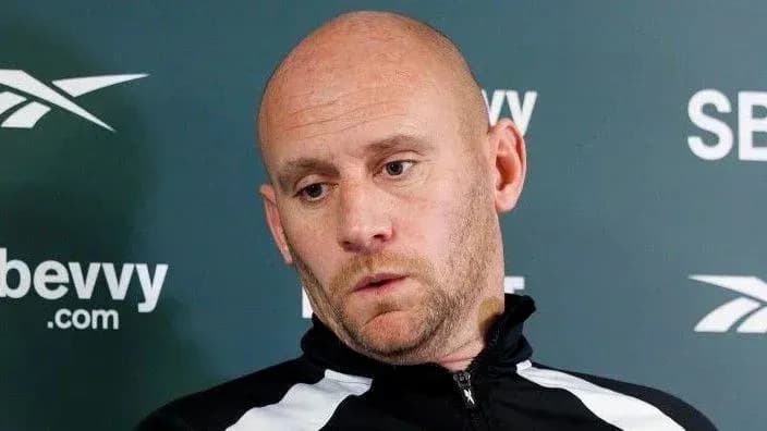 Entrenador en conferencia de prensa con fondo verde