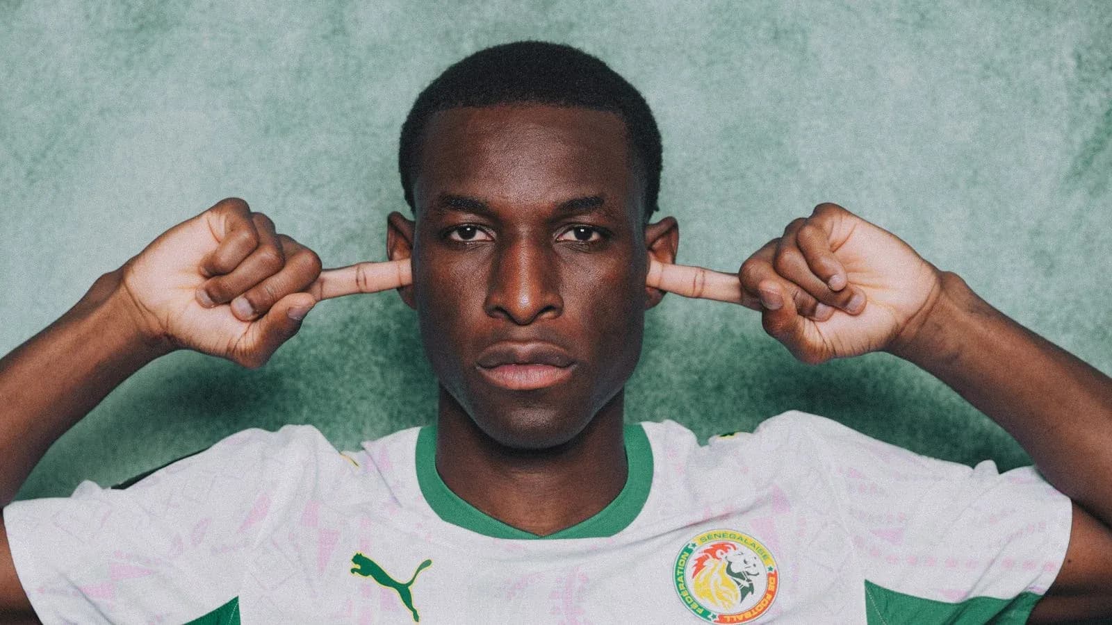 Jugador de fútbol con camiseta de Senegal tapándose los oídos