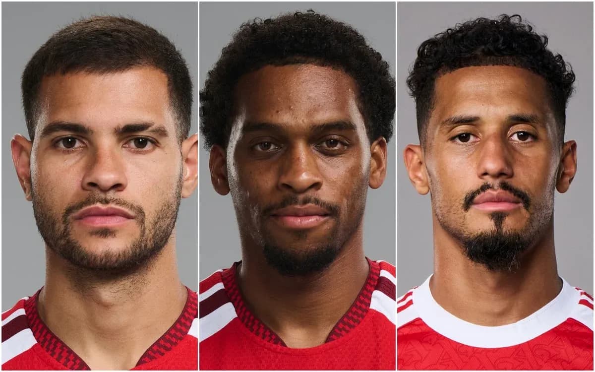 Tres jugadores posando con uniforme rojo en fondo gris