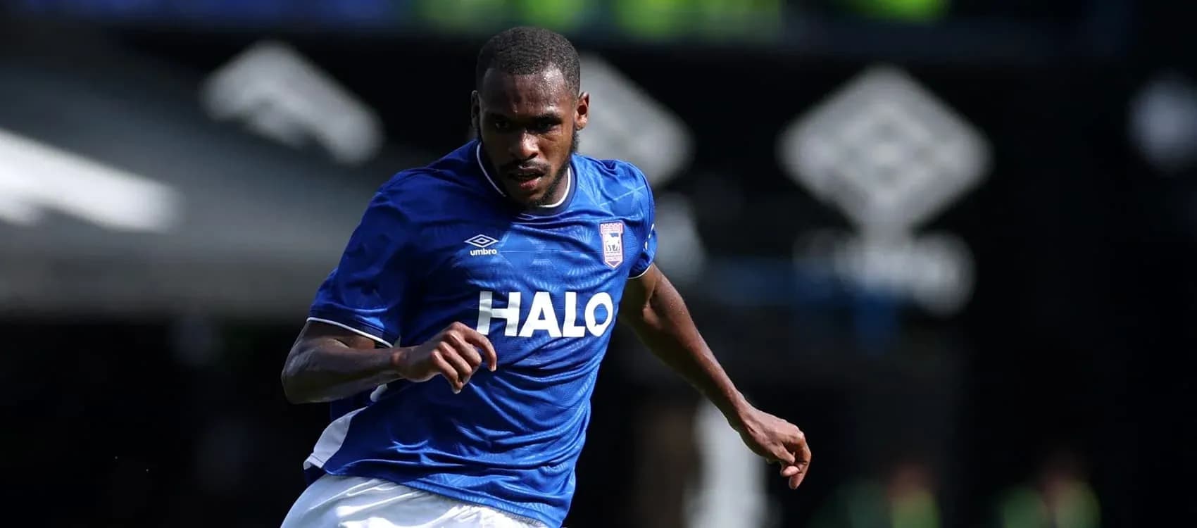 Jugador corriendo con balón en camiseta azul