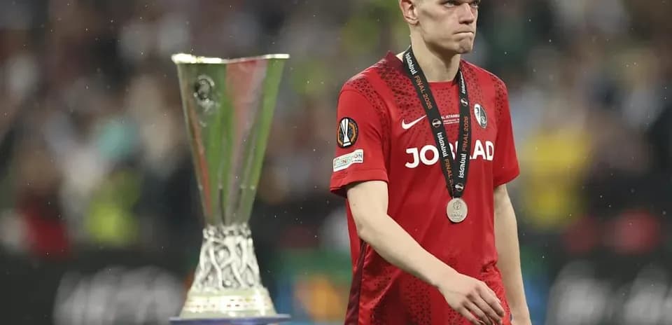Jugador con medalla caminando junto al trofeo UEFA