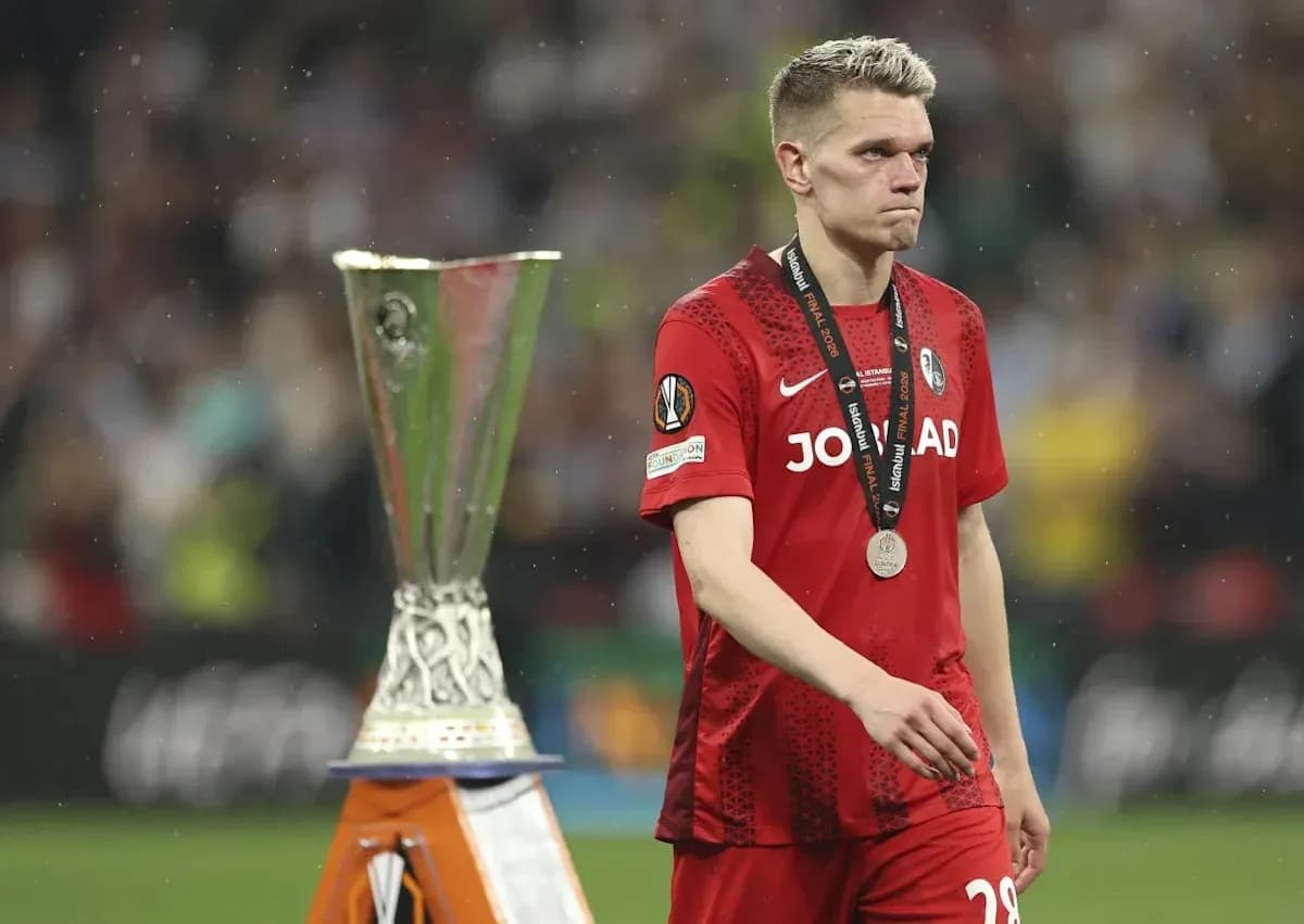 Jugador con medalla caminando junto al trofeo UEFA