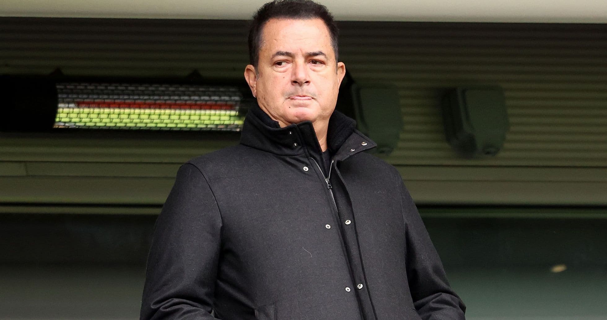 Hombre en abrigo negro observando desde la tribuna