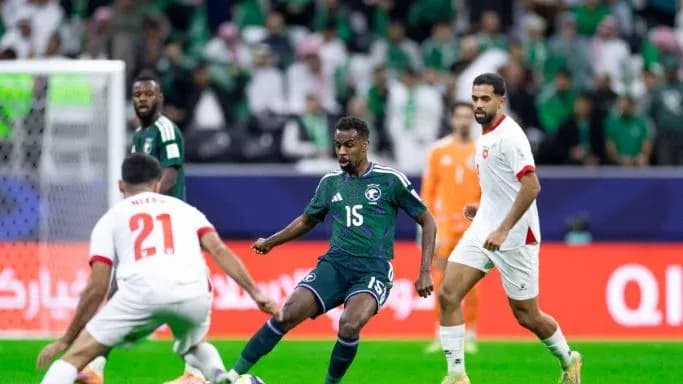 Jugador saudí driblando entre dos oponentes en partido
