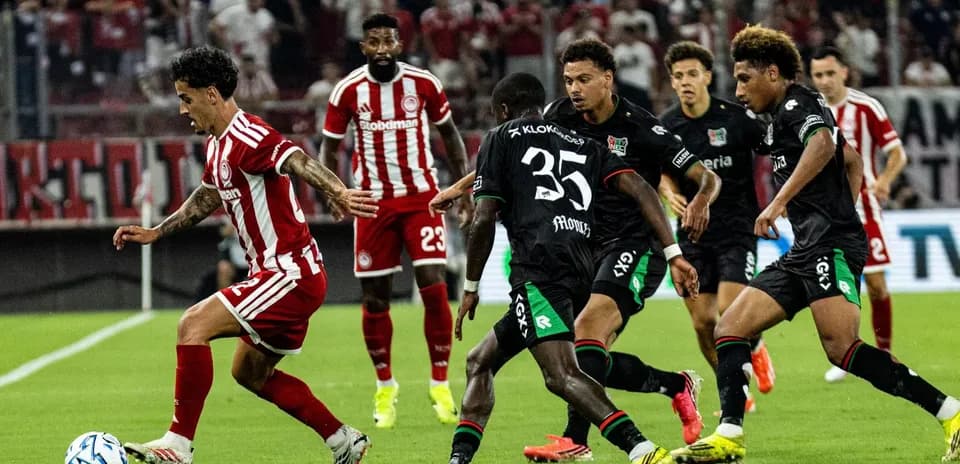 Jugador de Olympiakos esquivando a defensores de NEC