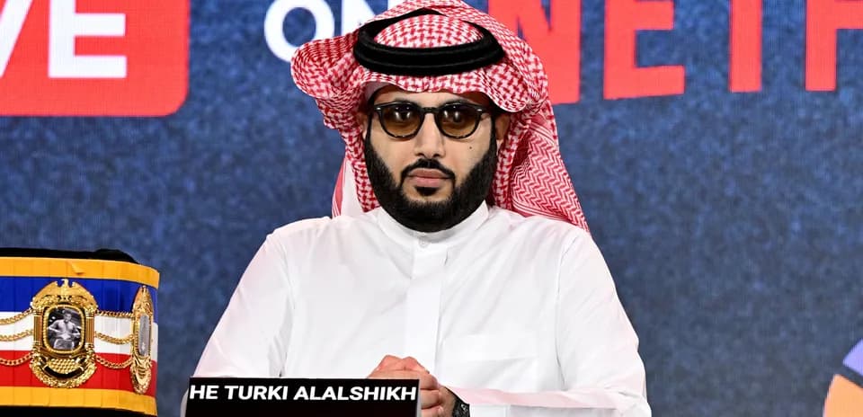 Hombre con gafas sentado en conferencia de prensa