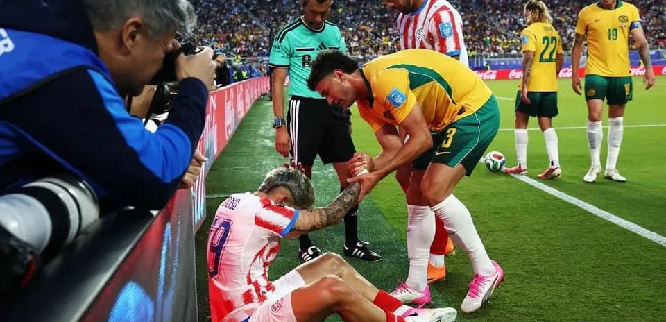 Jugador caído siendo asistido por rival y árbitro