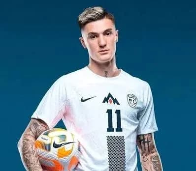 Jugador sosteniendo un balón en camiseta blanca