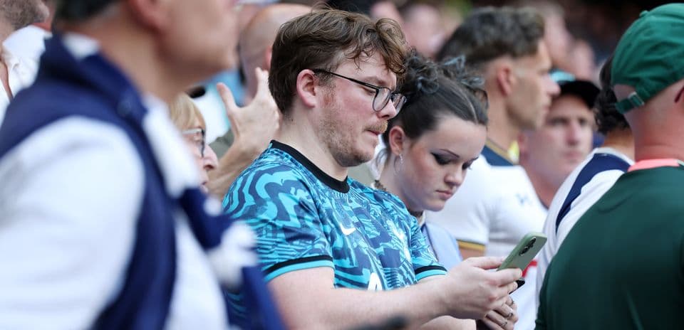 Espectadores en un evento deportivo revisando sus teléfonos