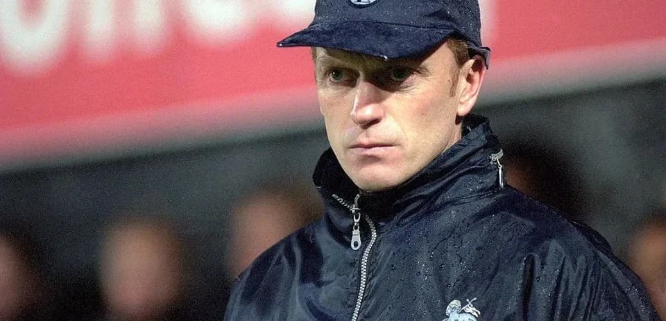 Entrenador de fútbol con chaqueta y gorra en campo