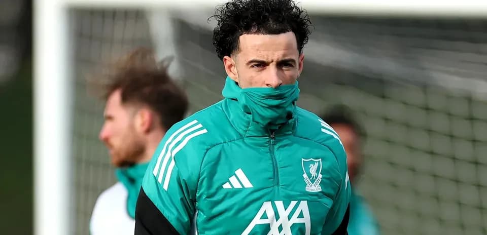 Jugador entrenando con abrigo de Liverpool en campo