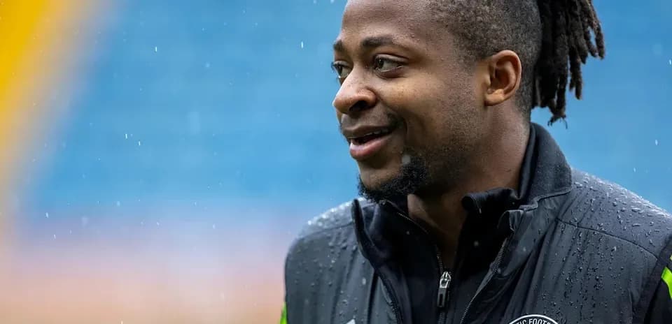 Jugador sonriendo con chaqueta de entrenamiento en campo