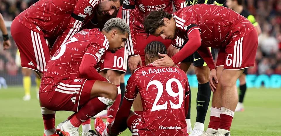 Jugadores de Liverpool consolando a compañero en el suelo
