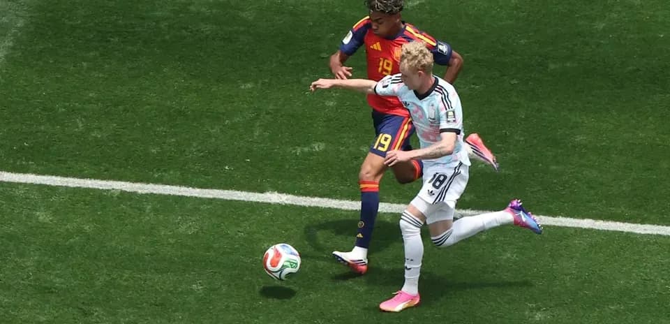 Jugador de España persiguiendo a jugador alemán en el campo