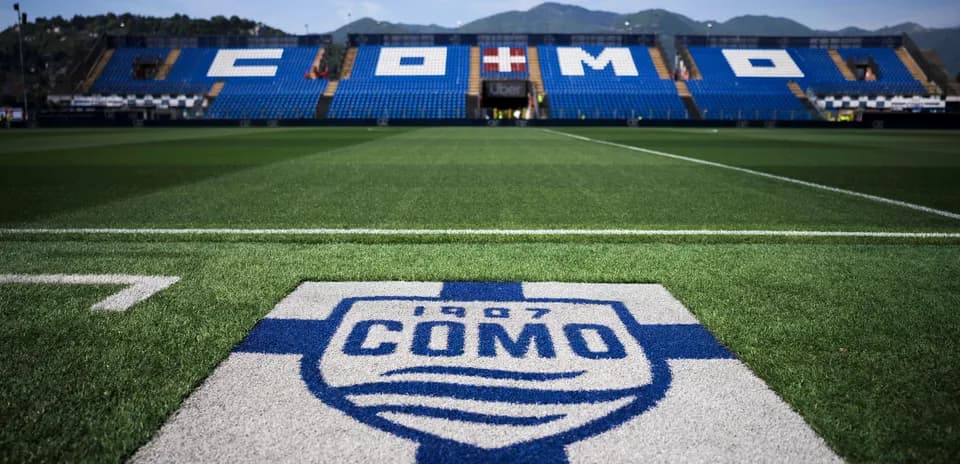 Campo de fútbol con logo del FC Como en primer plano