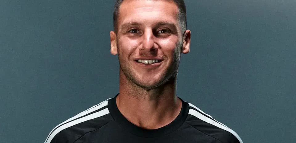 Jugador sonriendo con uniforme negro de fútbol