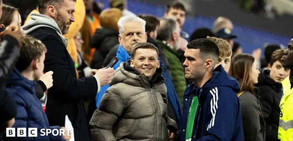 A boy smiling near spectators at a match