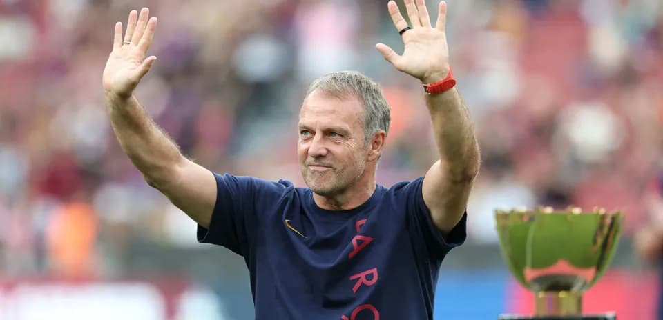 Entrenador saludando junto a trofeo en el campo