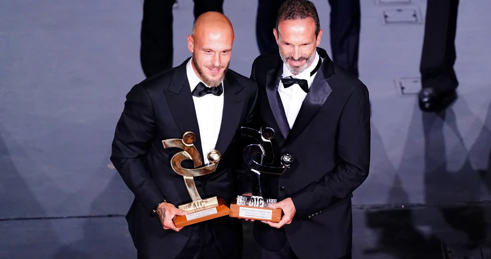 Dos personas sosteniendo premios en una ceremonia