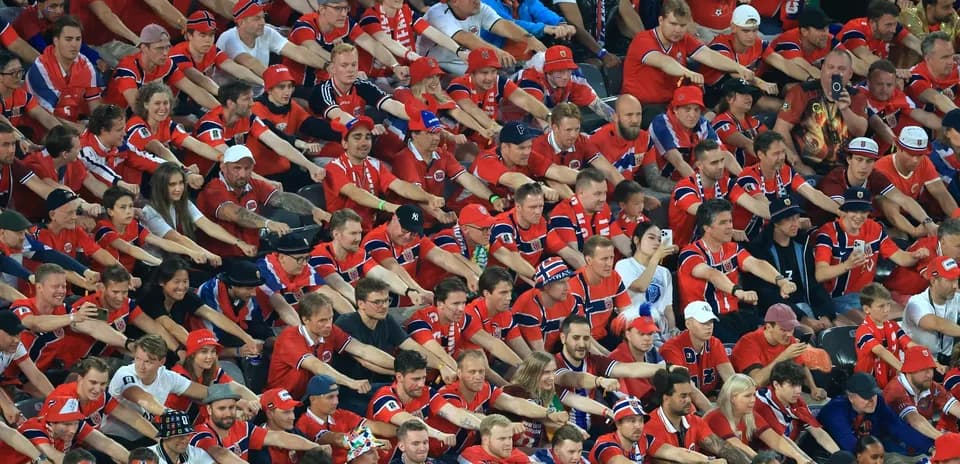 Aficionados animando en el estadio con camisetas rojas
