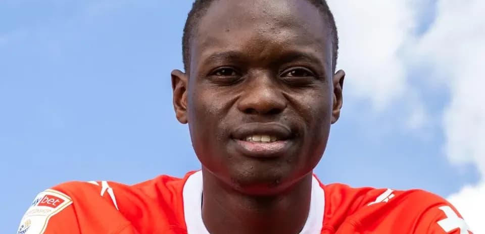 Jugador sonriendo con camiseta roja frente a cielo azul
