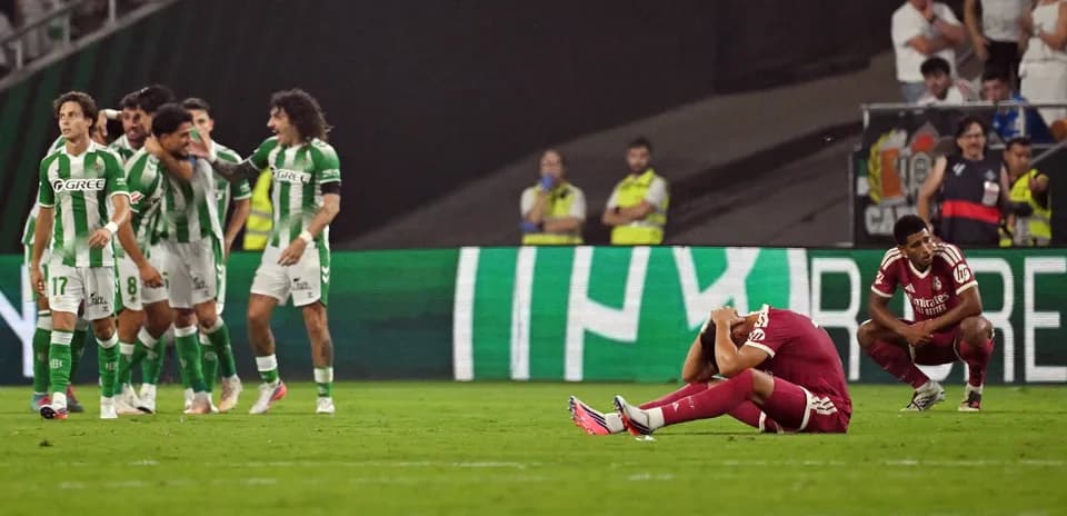 Jugadores de Betis celebrando, mientras adversario se lamenta