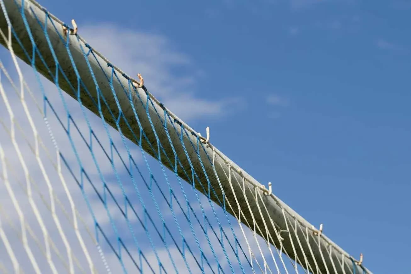 Red de un arco de fútbol bajo un cielo azul
