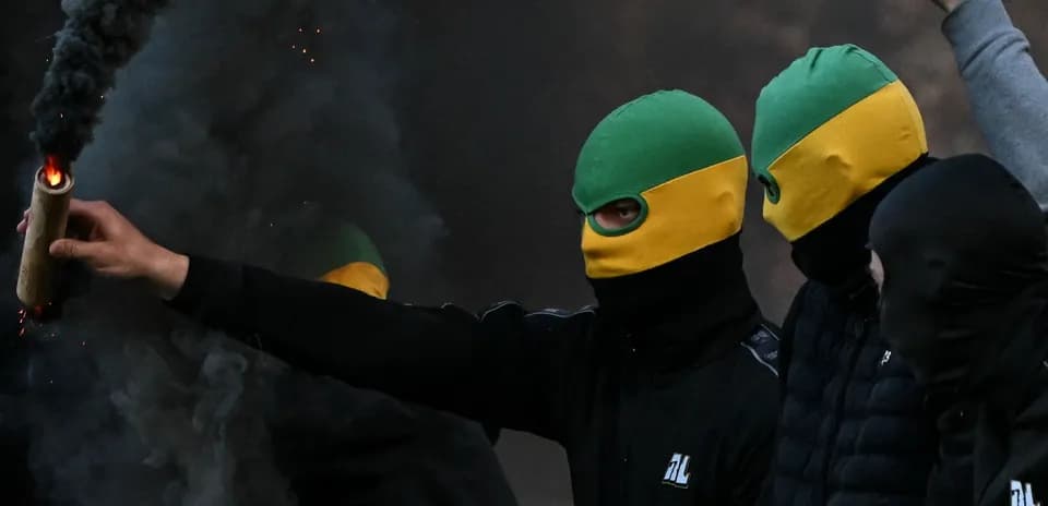 Grupo de personas con máscaras y bengala encendida