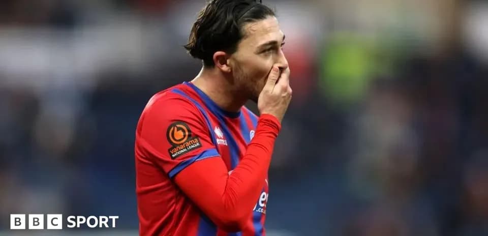 Jugador con camiseta roja tocándose la cara