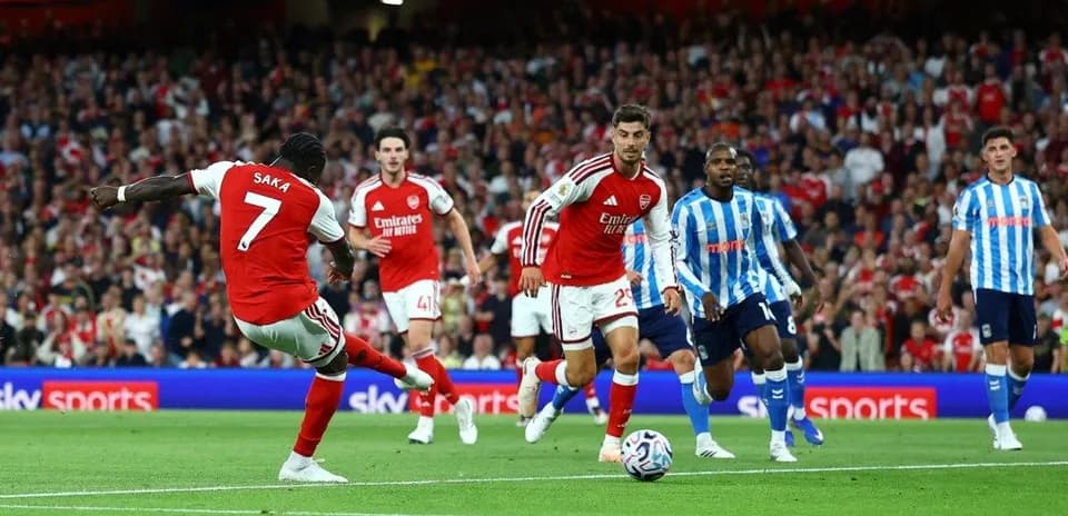 Saka disparando durante un partido de Arsenal