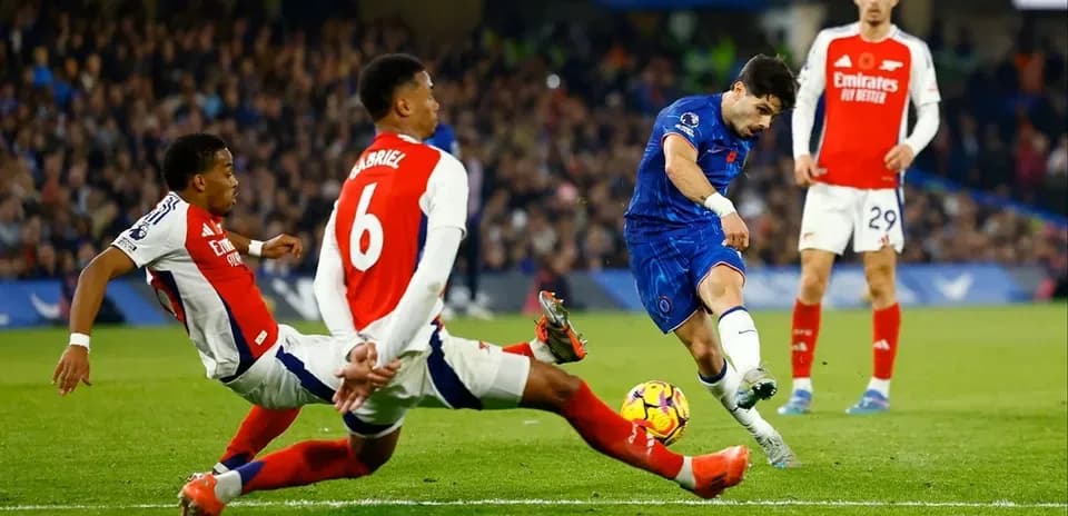 Jugador de Chelsea disparando mientras es tackleado
