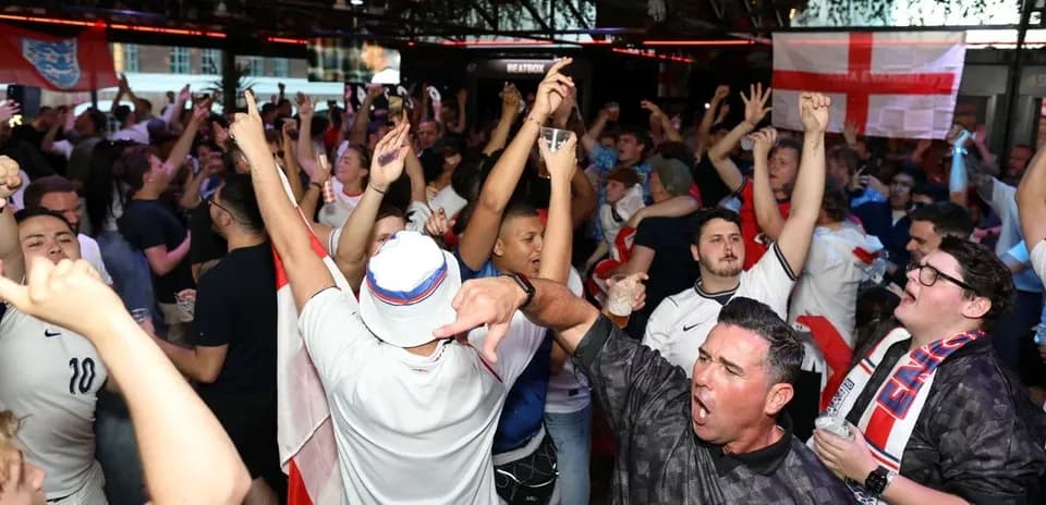 Agroup of fans celebrating in a crowded bar