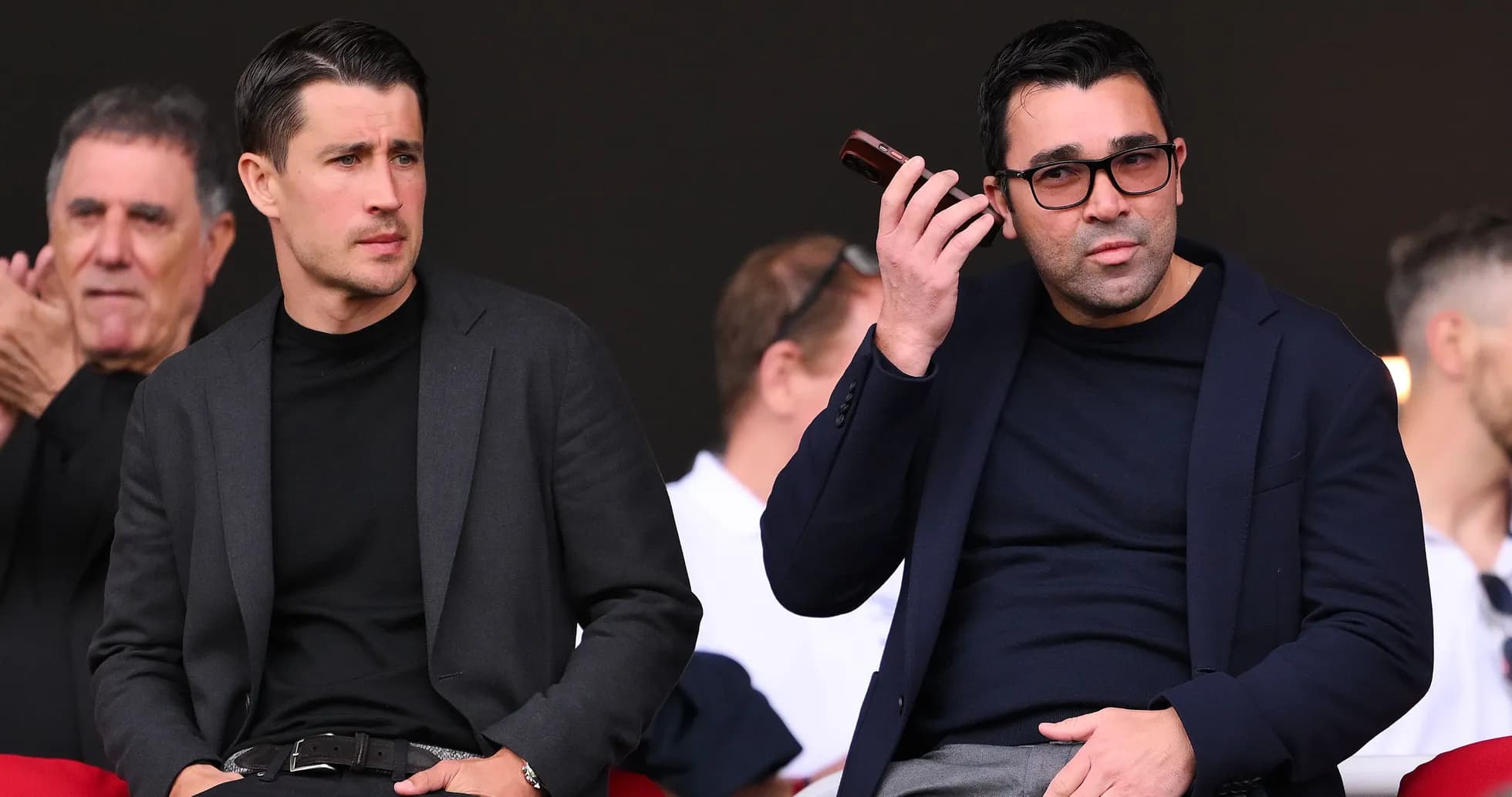 Dos hombres sentados en un evento deportivo