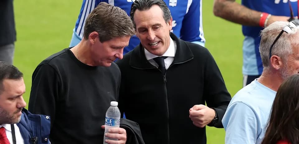 Dos entrenadores conversando en el campo de juego