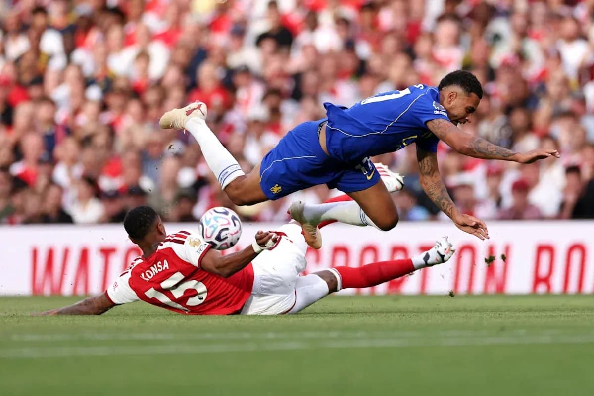 Jugador de Arsenal en el suelo, rival saltando sobre él