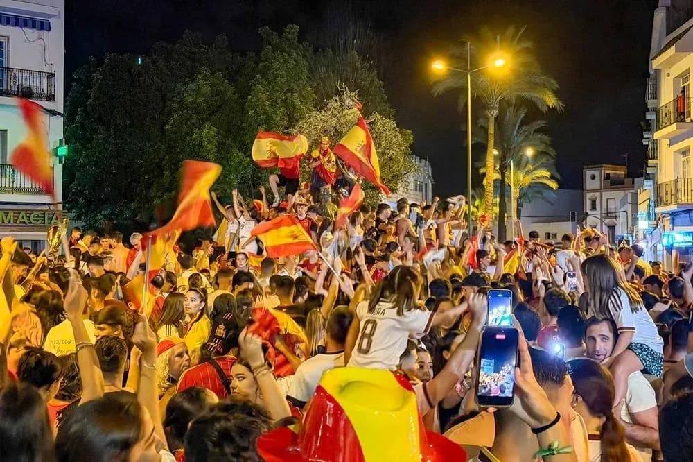 Multitud celebrando con banderas en la calle