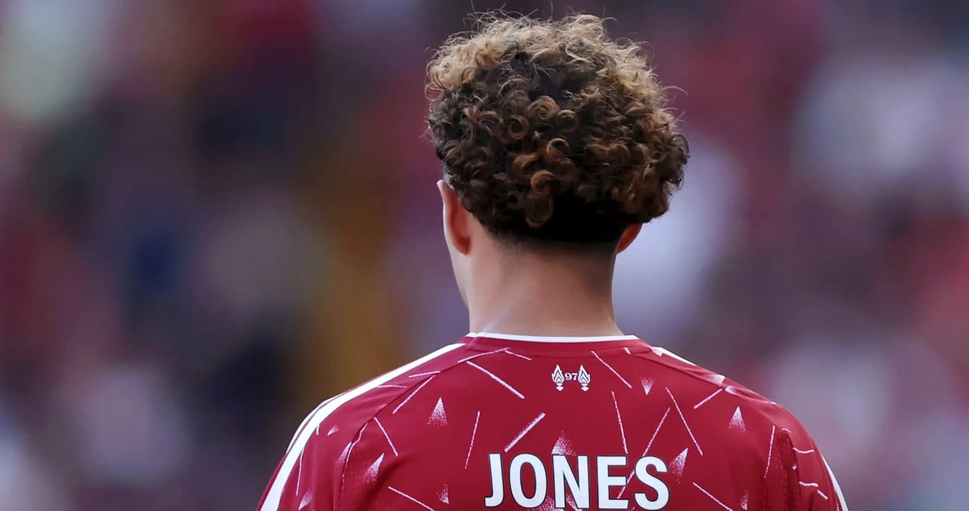 Jugador con camiseta roja de espaldas en el campo