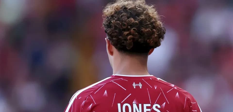 Jugador con camiseta roja de espaldas en el campo