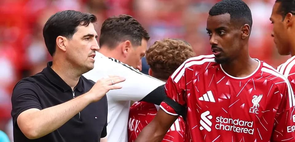 Entrenador hablando con jugador de Liverpool en el banquillo