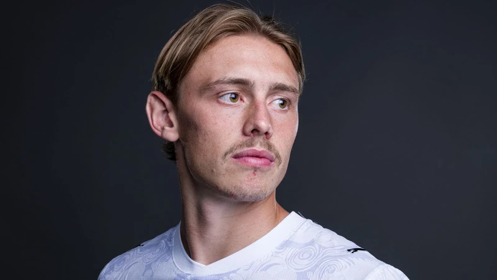 Jugador posando con camiseta blanca en fondo oscuro
