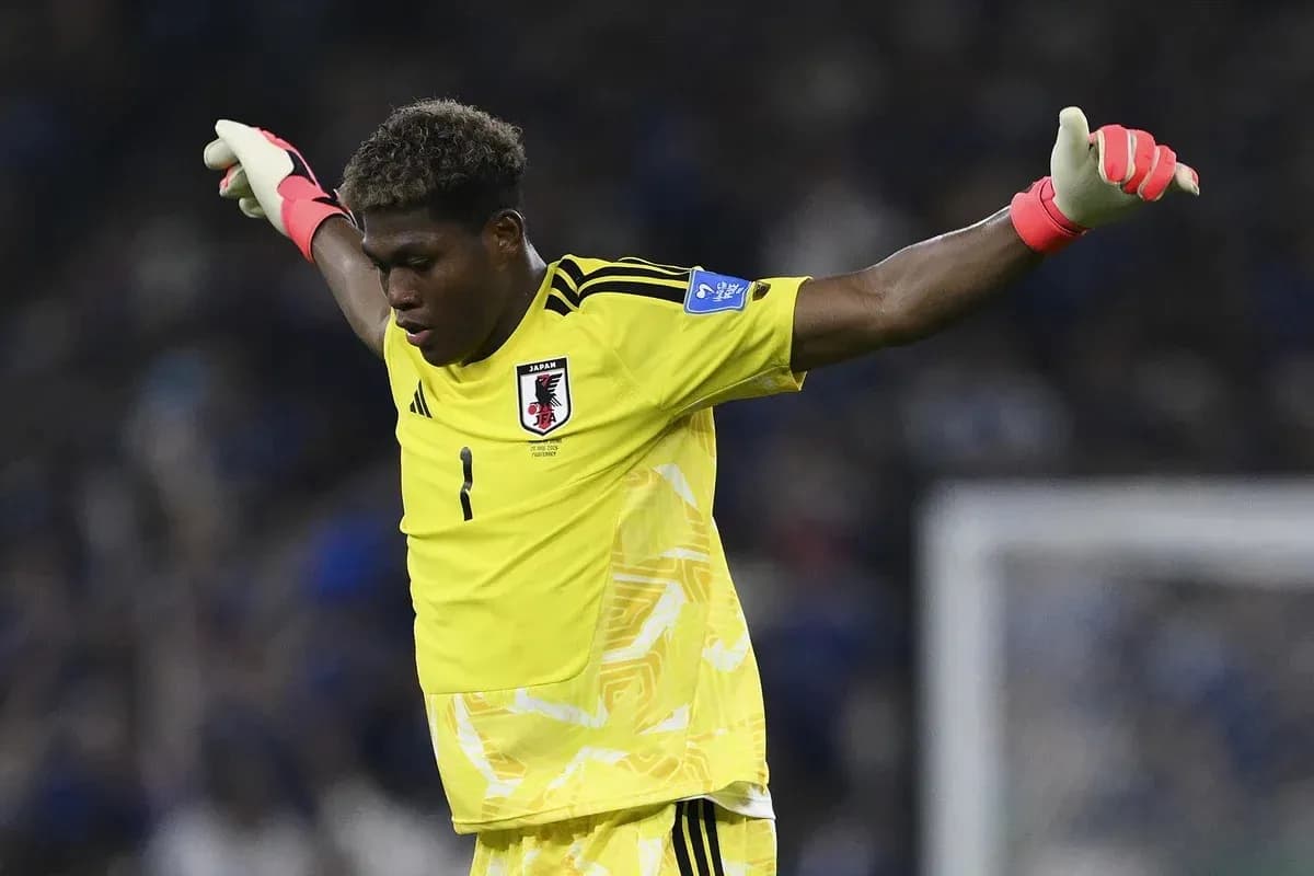 Portero de Japón con guantes levantando los brazos