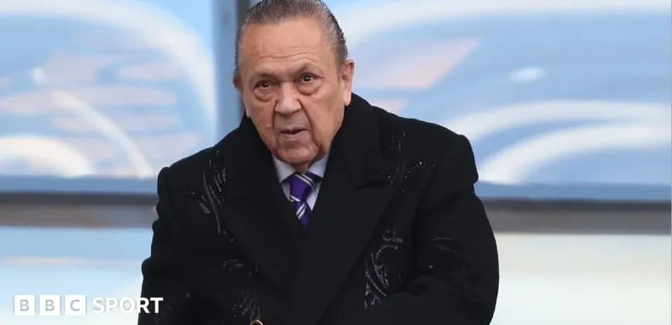 Hombre mayor en abrigo oscuro en un evento deportivo