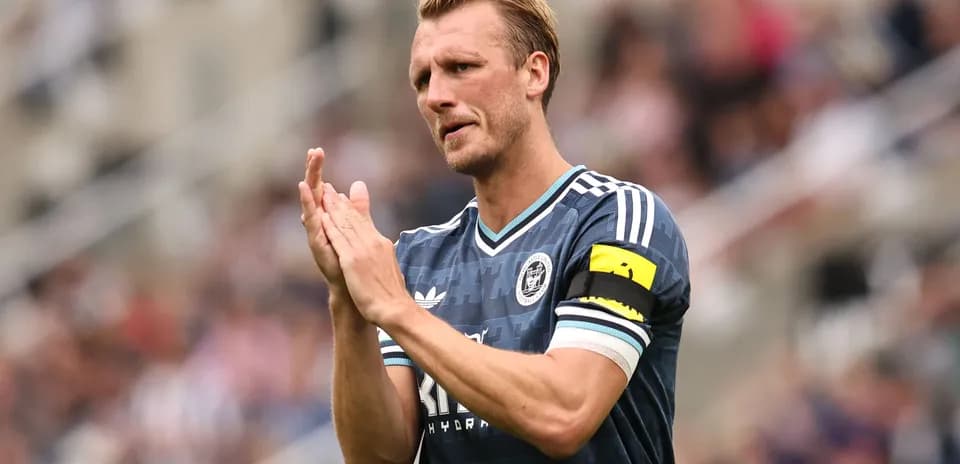 Jugador aplaudiendo con camiseta de equipo y cinta de capitán