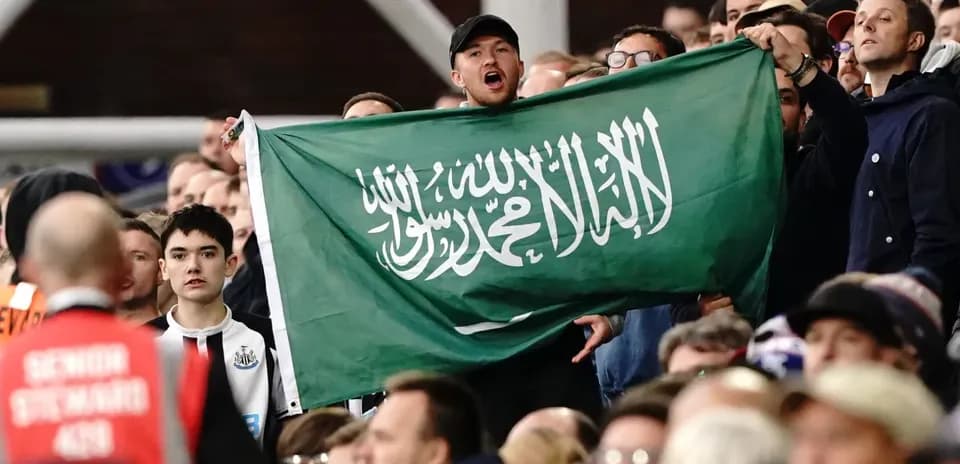 Afan de pie sosteniendo una bandera saudí en el estadio