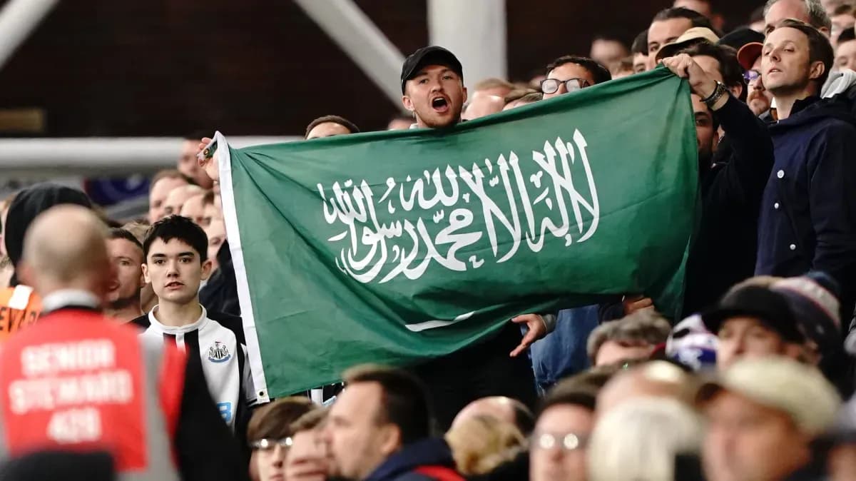 Afan de pie sosteniendo una bandera saudí en el estadio