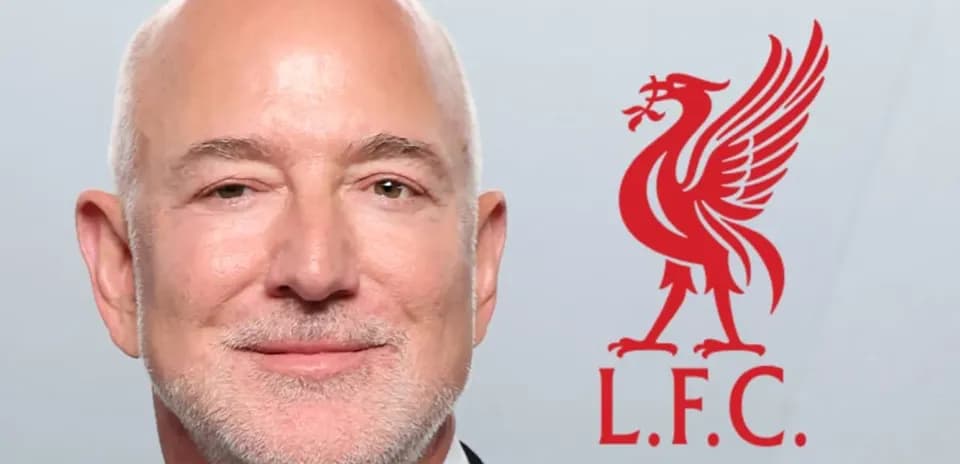 Hombre sonriendo con logo de Liverpool detrás