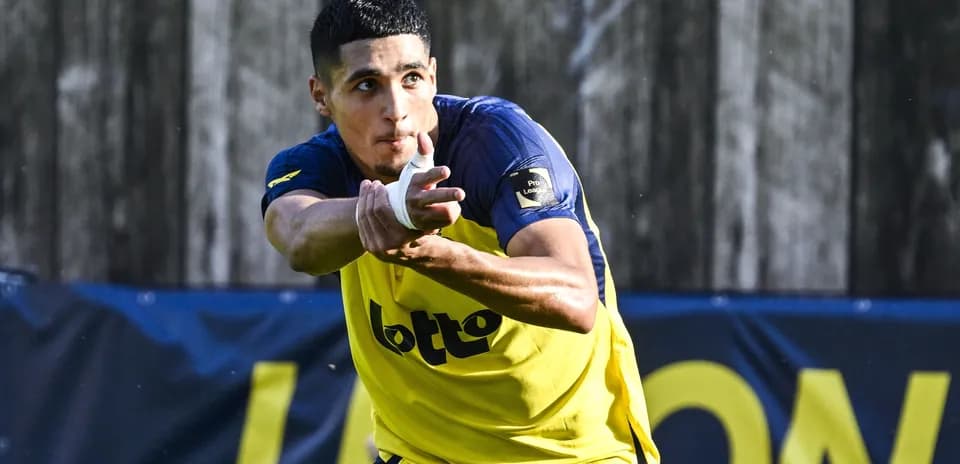 Jugador de fútbol entrenando con balón en mano