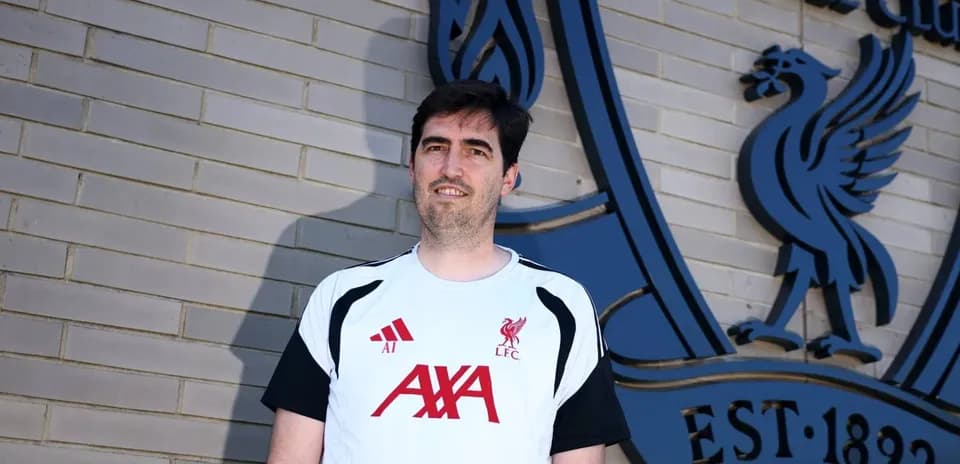Persona posando frente al logo del Liverpool FC