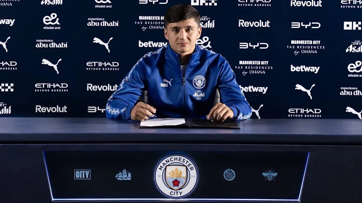 Jugador firmando contrato en mesa de prensa